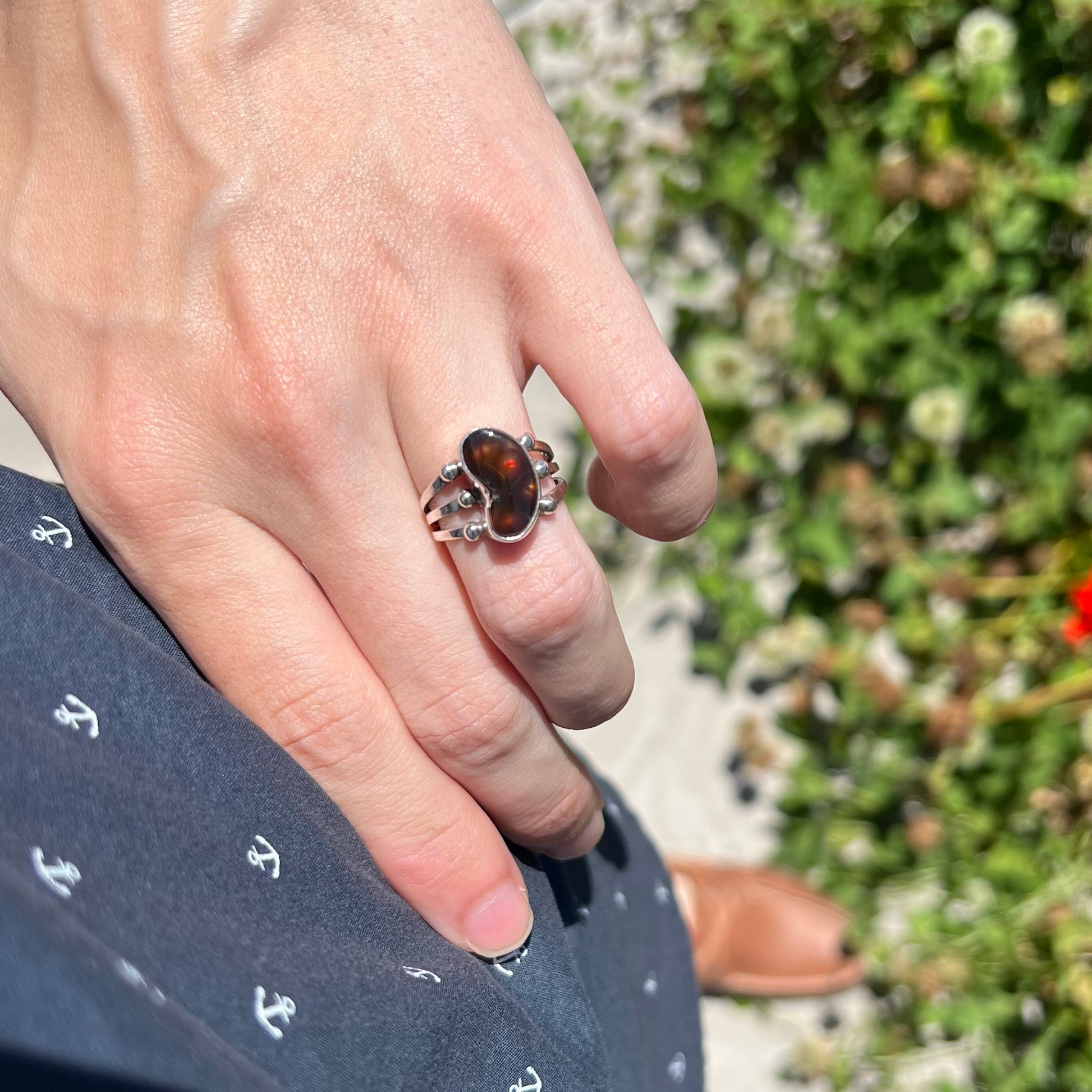 Lifestyle photo of fire agate ring worn on hip in natural sunlight.