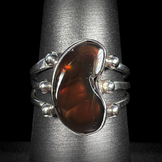 A sterling silver Mexican fire agate ring with red flash shown on gray ring holder.