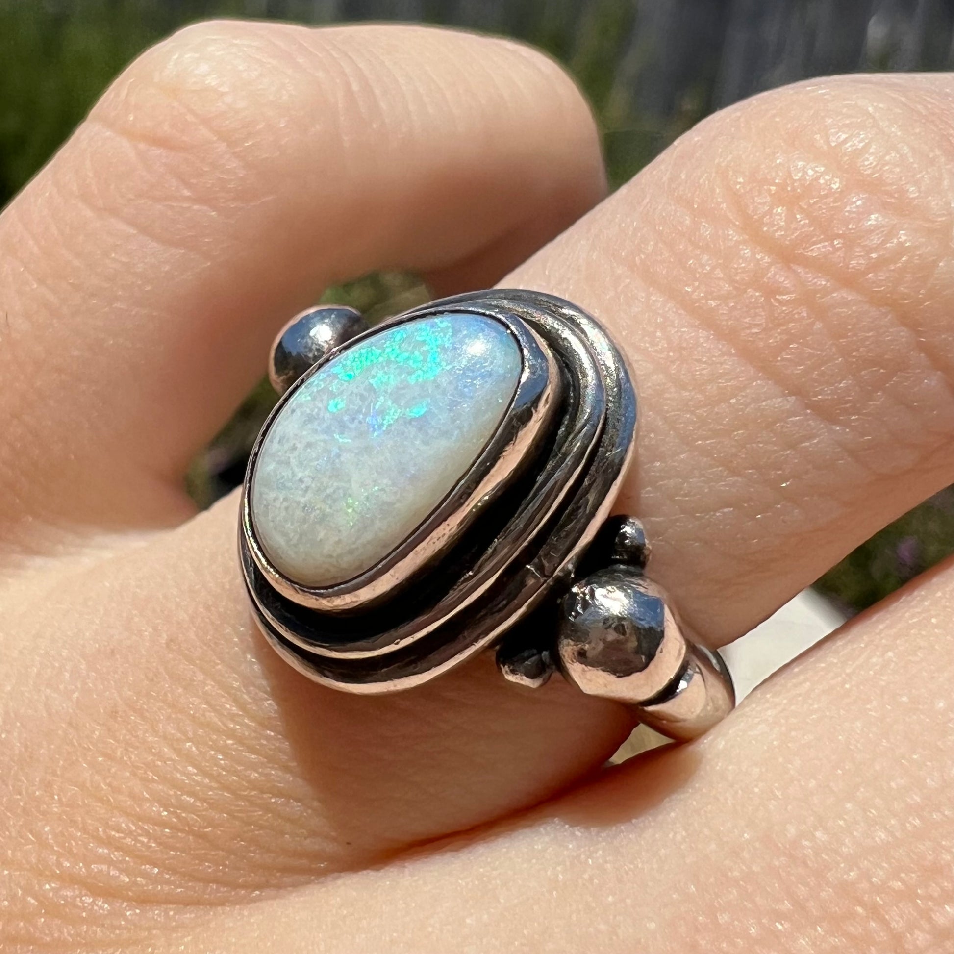 Angled view of a handmade Boho-style sterling silver opal ring set with an Australian opal in sunlight.