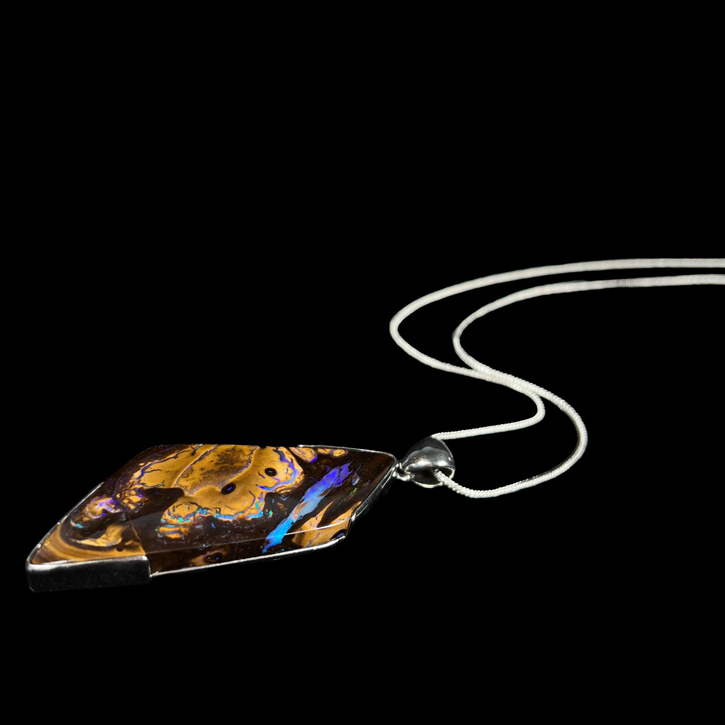 Australian boulder opal statement necklace in silver shown laying on black background