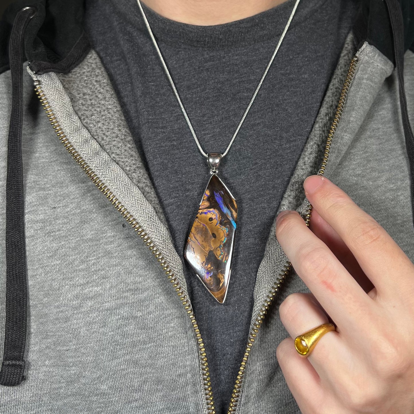 Close-up of person modeling brown Australian boulder opal statement pendant in silver on chain around neck