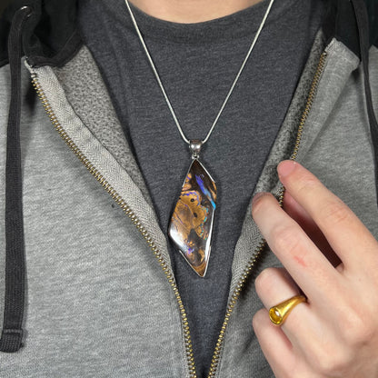 Close-up of person modeling brown Australian boulder opal statement pendant in silver on chain around neck