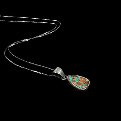 A handmade, satin finish sterling silver pendant set with a drop shaped boulder opal stone.