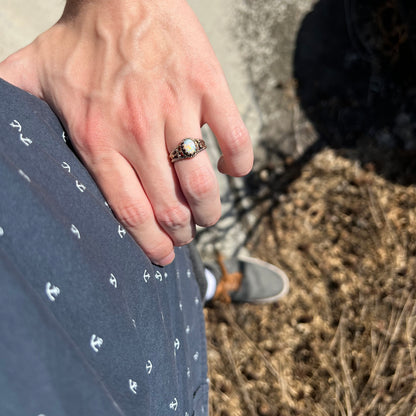 Close-up of person's hand resting on their hip in sunlight while wearing a brass Australian opal ring