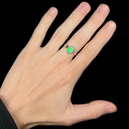 Hand wearing a sterling silver Australian opal ring with a bright green flash of color.