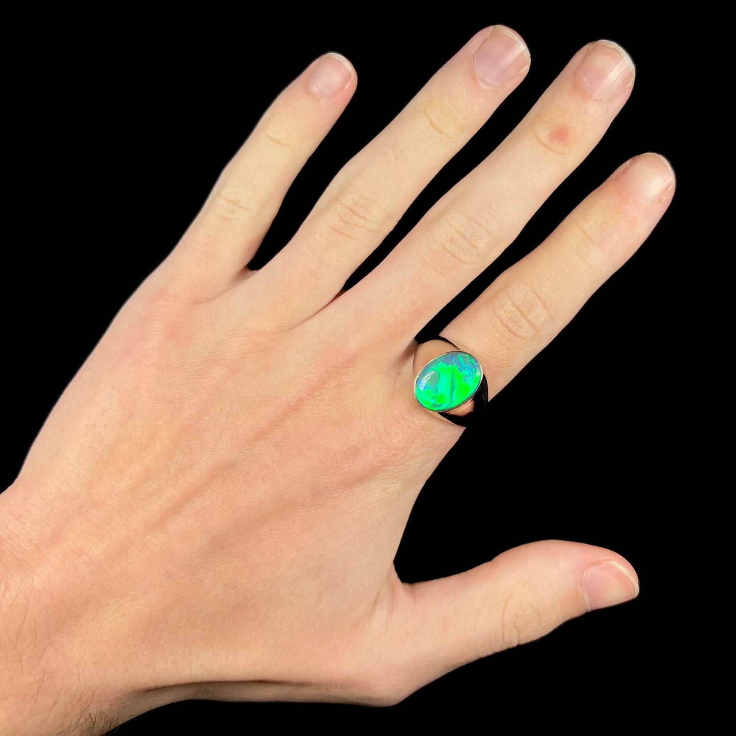 Hand wearing bright green Australian opal solitaire men's ring