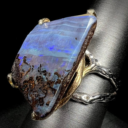 Angled view of a large, brutalist style boulder opal ring in two-tone sterling silver.