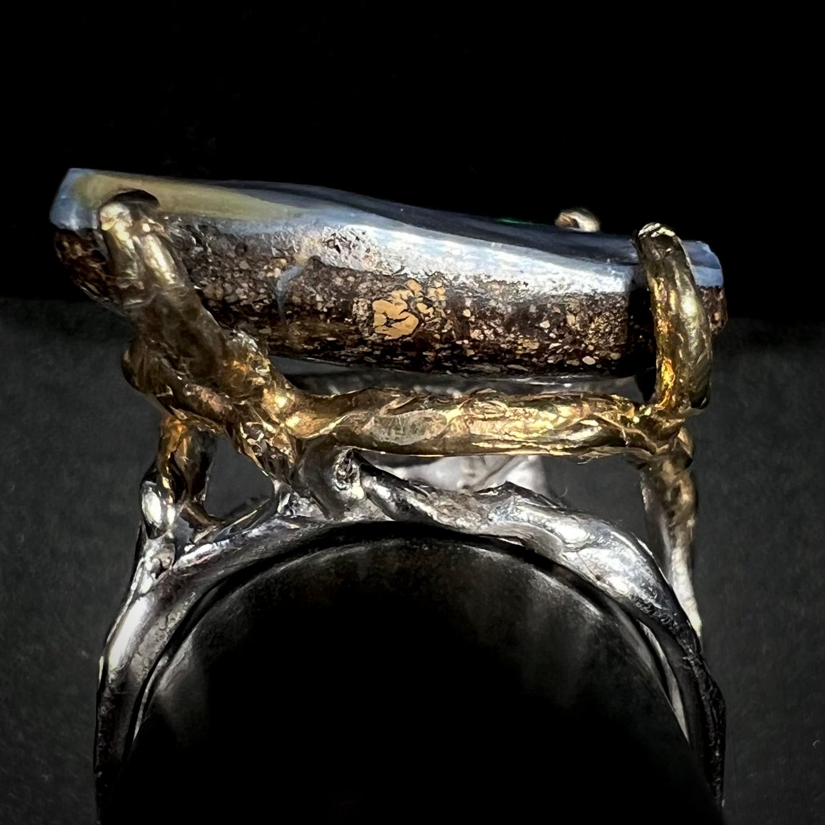 Side profile gallery view of a brutalist-style boulder opal ring with gold prongs and a silver shank.
