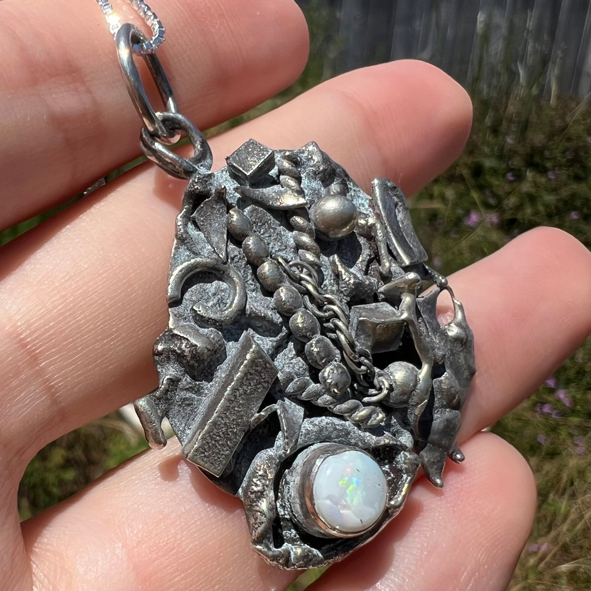 Angled sunlit macro view of a brutalist-style opal necklace set with a cracked Australian white opal.
