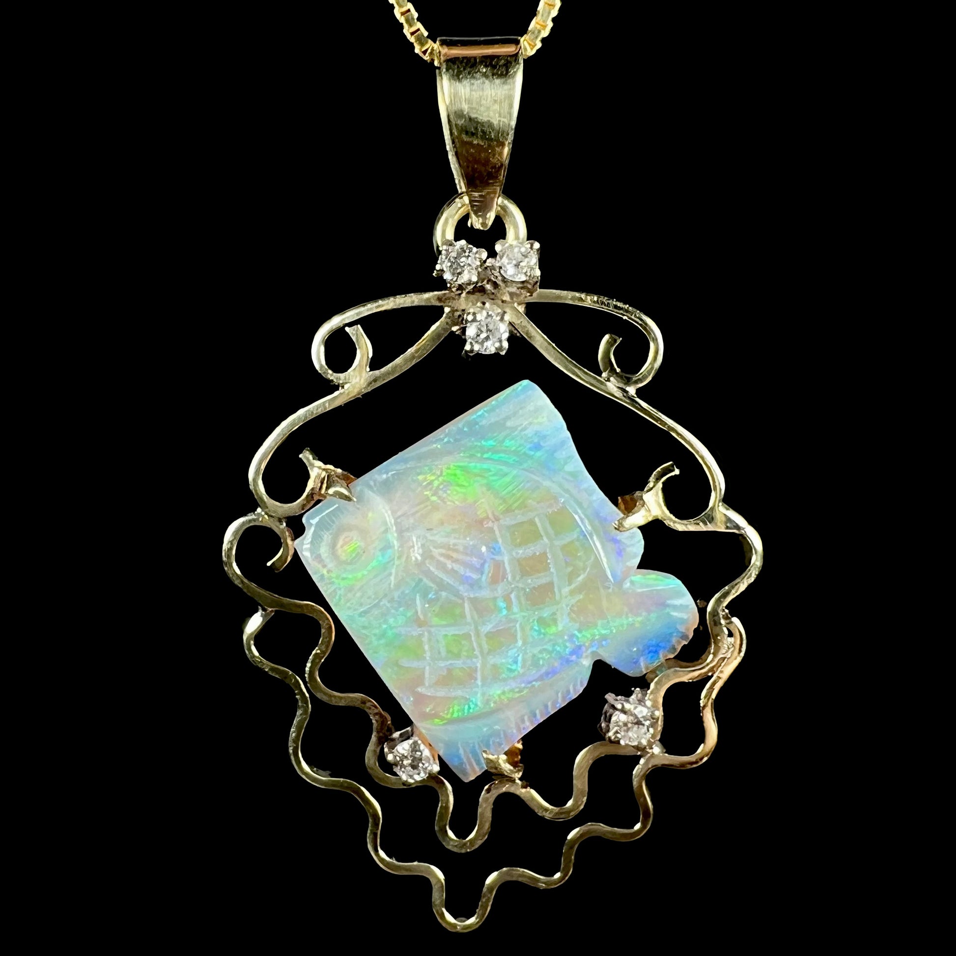 Close-up of an ocean-inspired carved opal fish and diamond-accented pendant in 14k gold