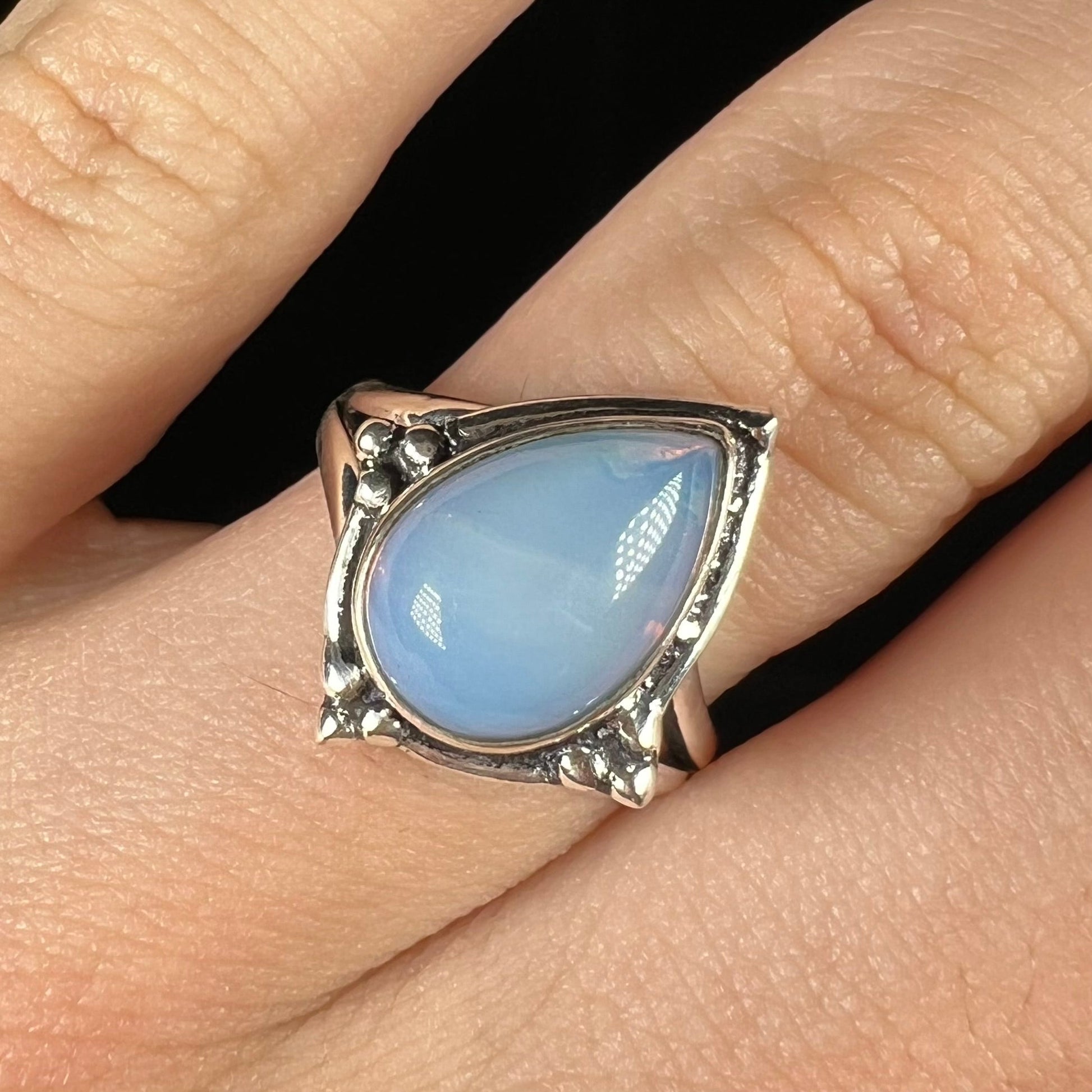 A handmade white metal ring set with a pear shaped opalite cabochon.