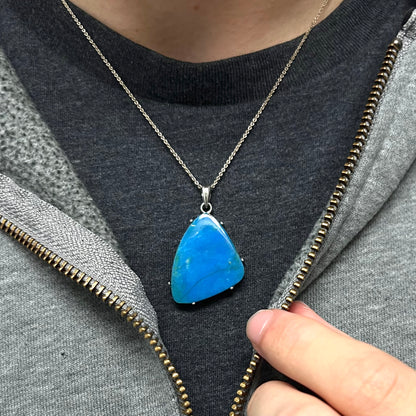 A Chilean opal necklace worn around the neck on a black T-shirt with a partially zipped sweatshirt.