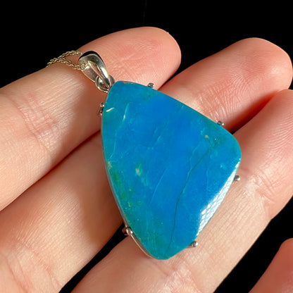 An angled macro close-up of a Chilean opal necklace resting on fingers.