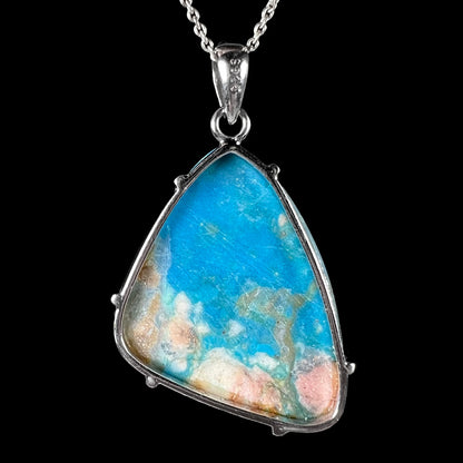 The back of a Chilean opal necklace, showing an open silver frame, tan matrix on the opal, and a ‘925’ stamp on the bail.