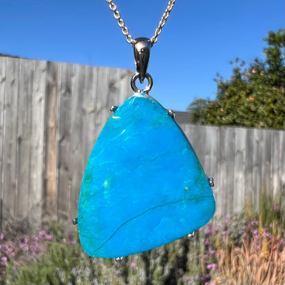 A macro close-up of a Chilean opal necklace outdoors, revealing its blue body color in natural light.