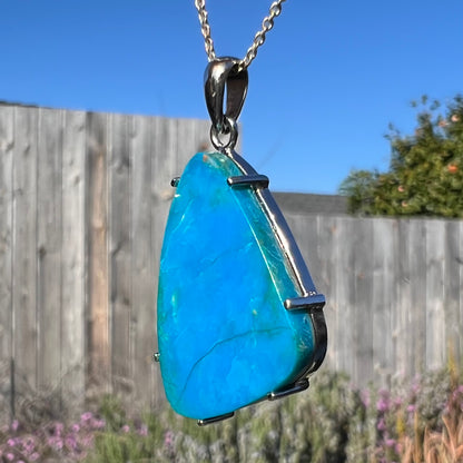 A side-angle macro view of a Chilean opal necklace in sunlight, showing its blue hues and matrix.