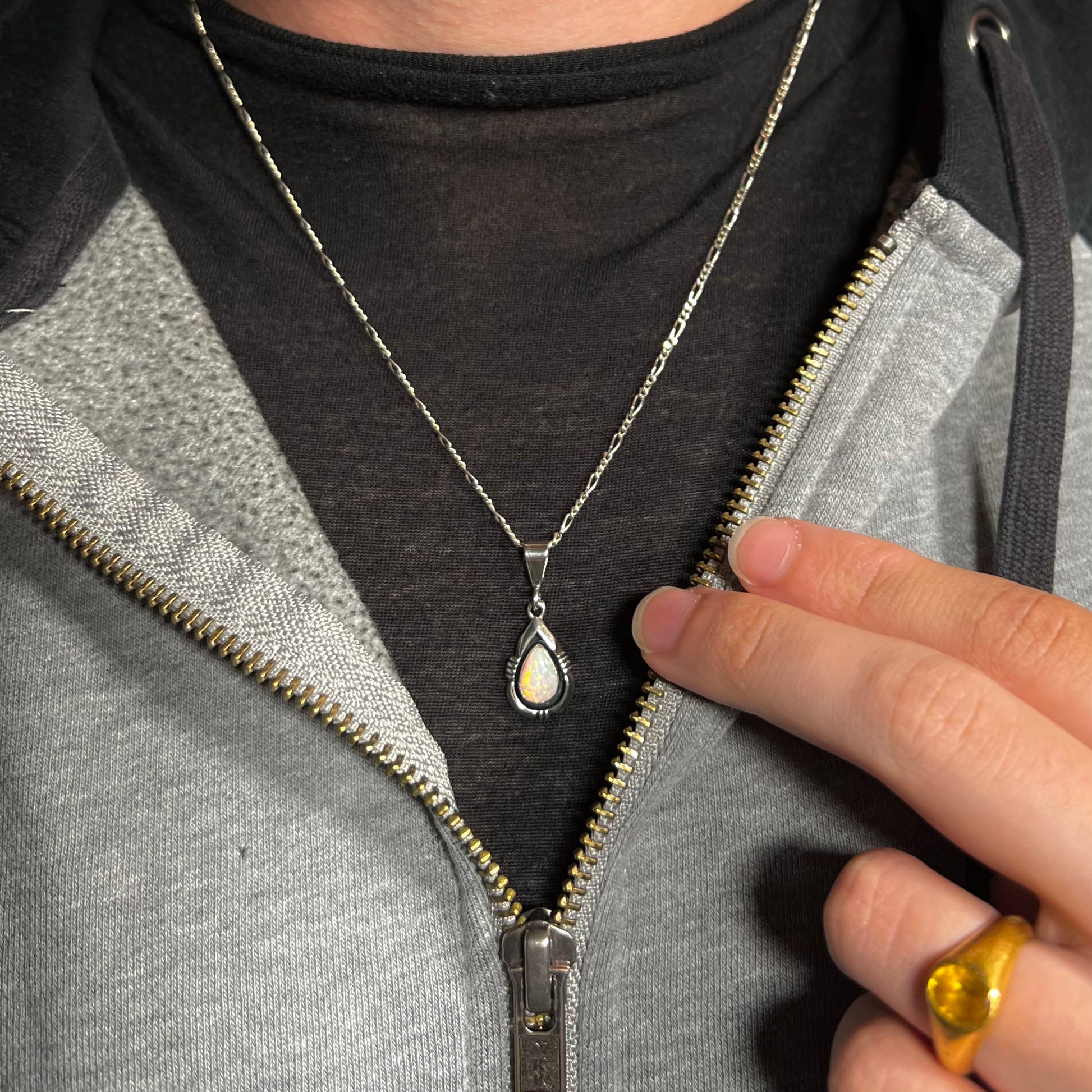 A sterling silver Navajo pendant set with a green Australian opal made by artist, Chris Charley, worn around a neck.