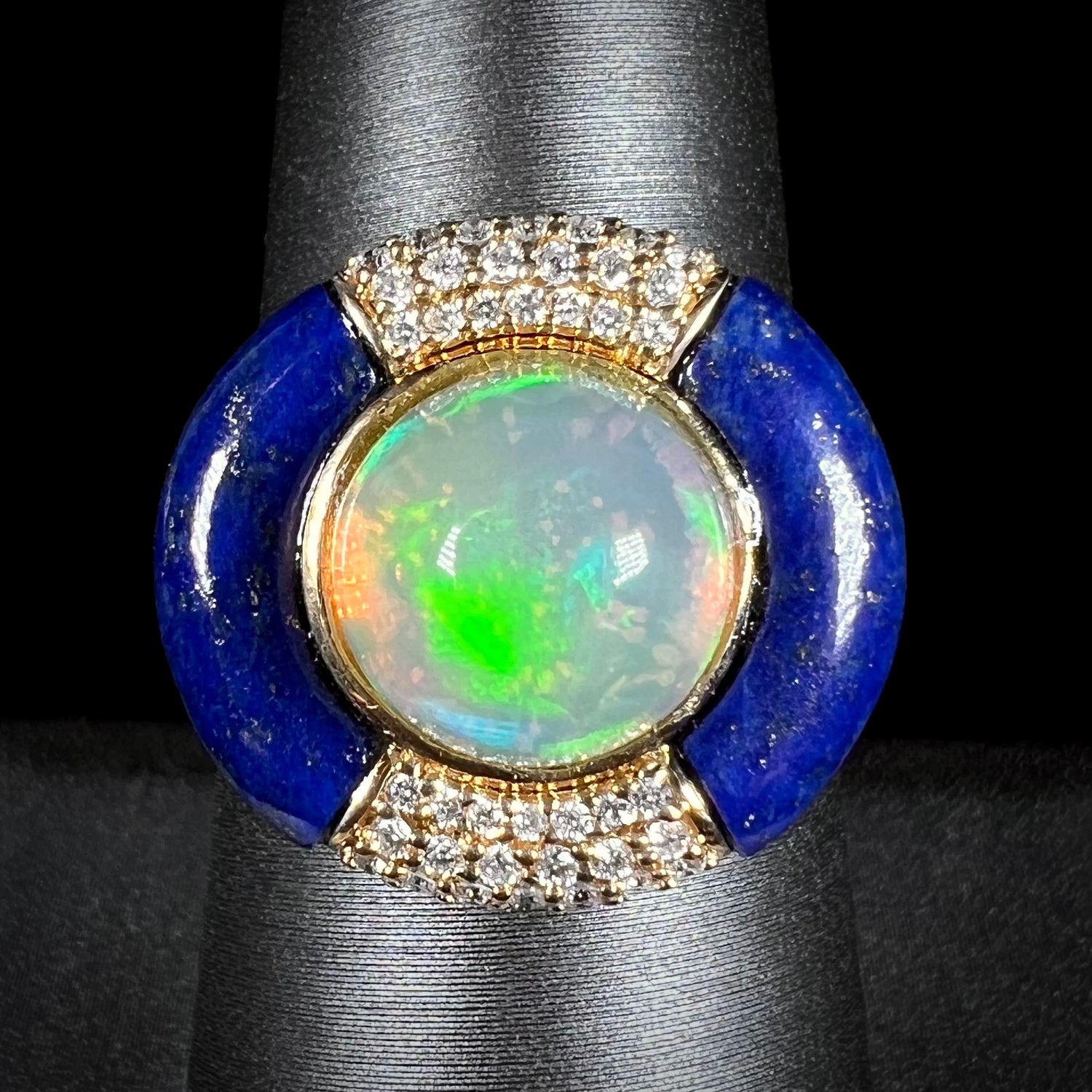 Front close-up macro view of a round Ethiopian opal and lapis lazuli with diamond halo design ring in 14k yellow gold, made by designer Cirari.