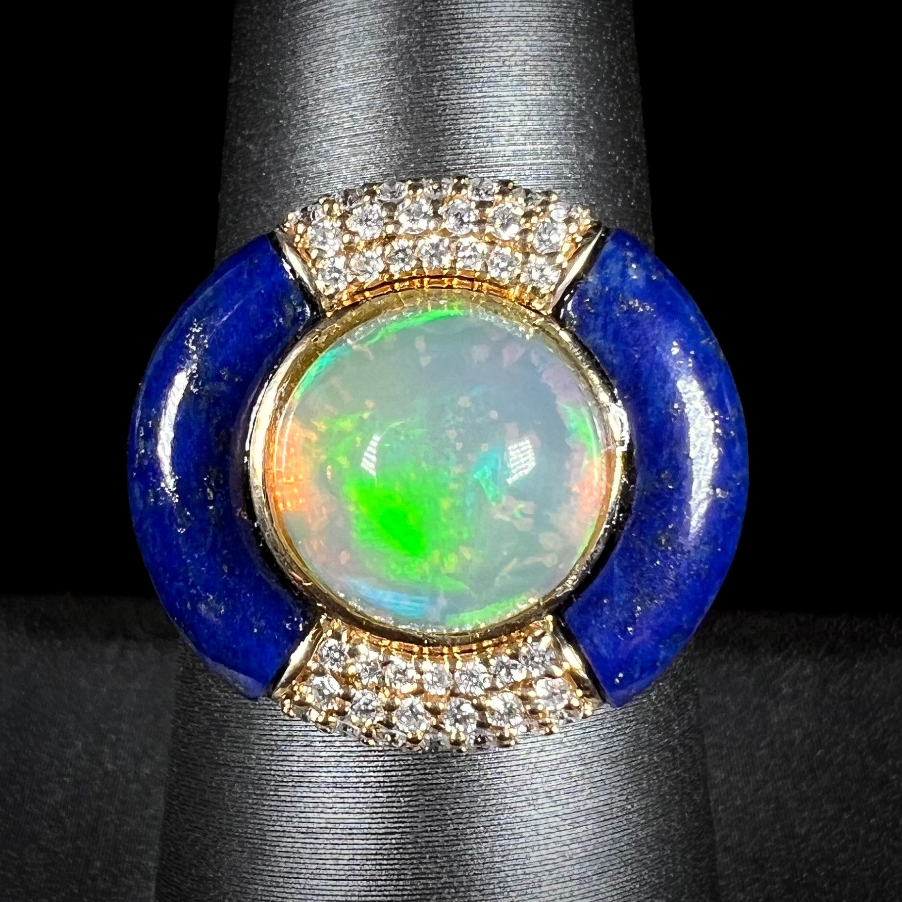 Front close-up macro view of a round Ethiopian opal and lapis lazuli with diamond halo design ring in 14k yellow gold, made by designer Cirari.