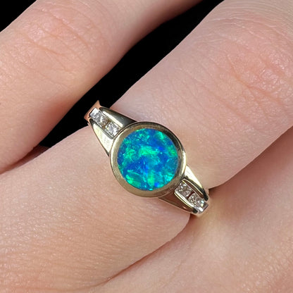 A clean-face Australian boulder opal ring with green color play over an N4 black body tone, shown close-up on a finger.