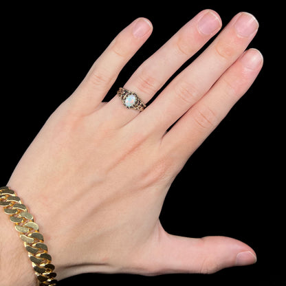 Hand wearing an estate base metal solitaire ring set with a colorful Australian opal
