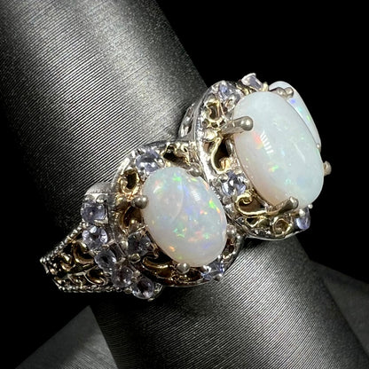 Angled close-up of a Coober Pedy, Australian opal and tanzanite ring shown on a ring display.  One of the opals has an eye-visible crack inclusion.