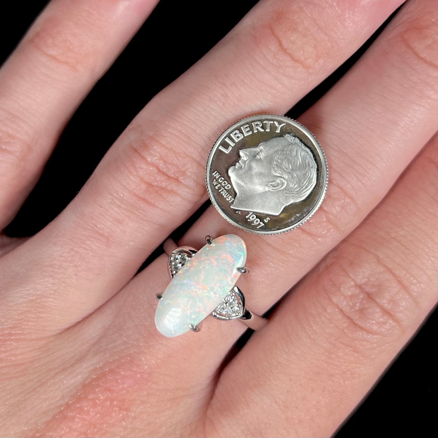 A Coober Pedy white opal platinum ring set with diamond accents.  The opal plays soft pink colors.