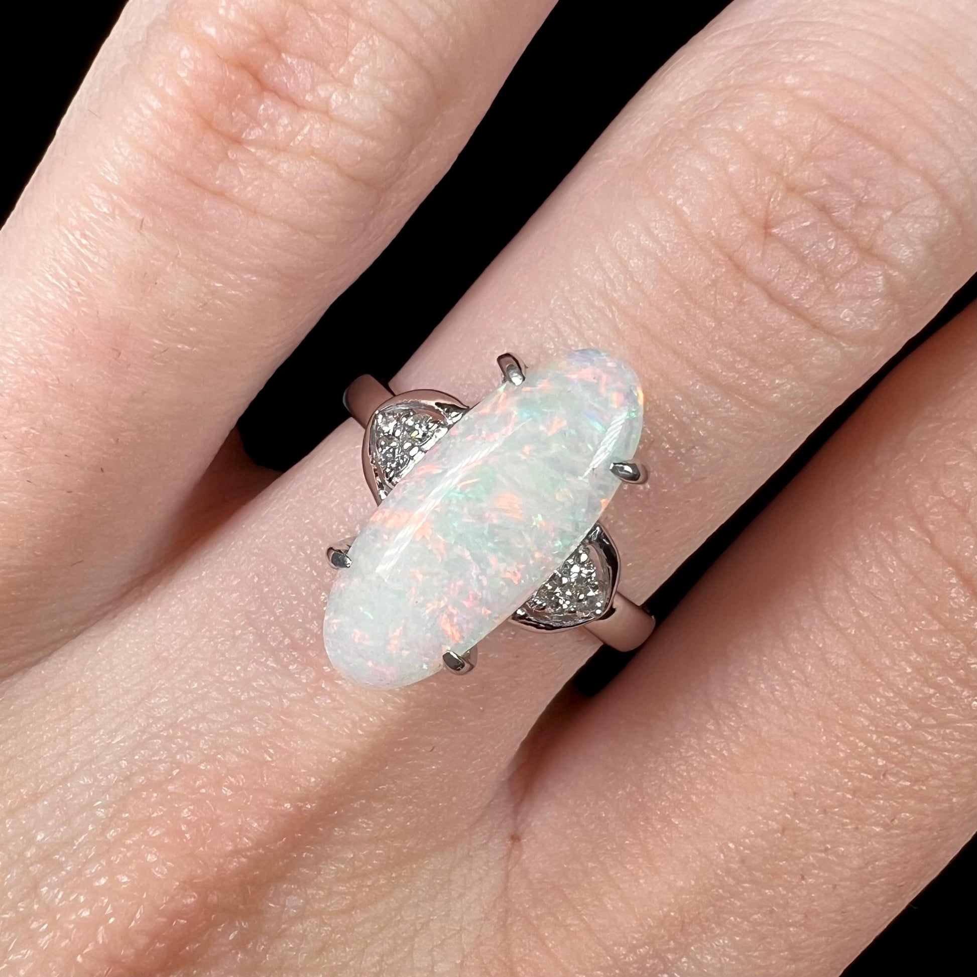 A Coober Pedy white opal platinum ring set with diamond accents.  The opal plays soft pink colors.