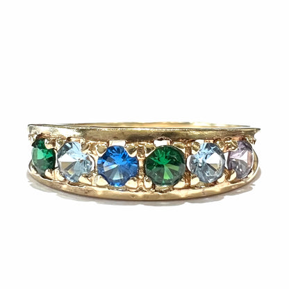 A ladies' yellow gold band set with green, dark blue, light blue, and light purple stones.