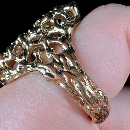 Close-up of the side of a large, gold-tone men's ring's shank showing a copper-colored wear point.