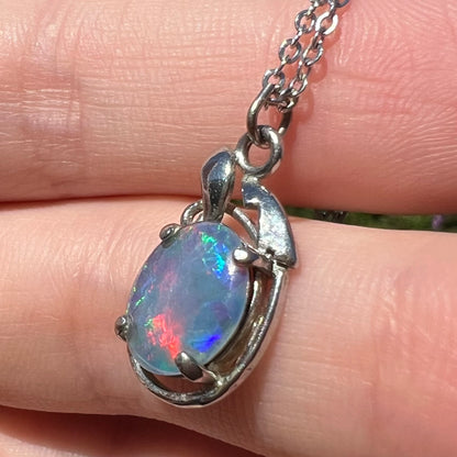 Costume opal triplet necklace shown close-up in hand from angle under sunlight