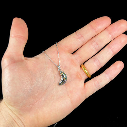 A sterling silver necklace bezel set with a natural Koroit boulder opal stone.  The stone is shaped like a crescent moon.
