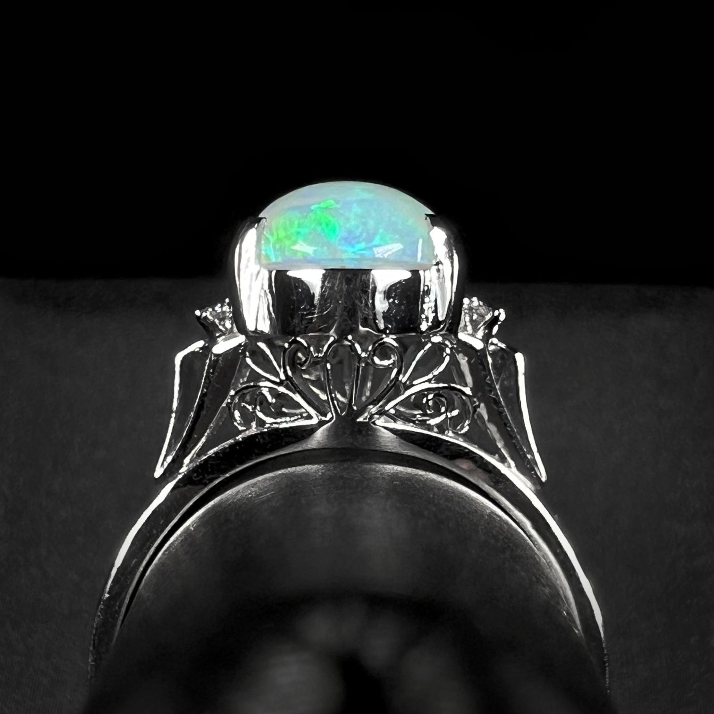 A platinum filigree ring set with a Lightning Ridge crystal opal and diamond accents.