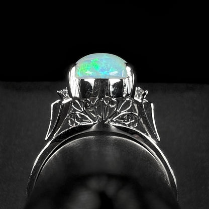 A platinum filigree ring set with a Lightning Ridge crystal opal and diamond accents.