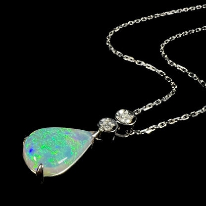 A platinum drop pendant mounted with two diamond accents and a pear shaped green-blue crystal opal.