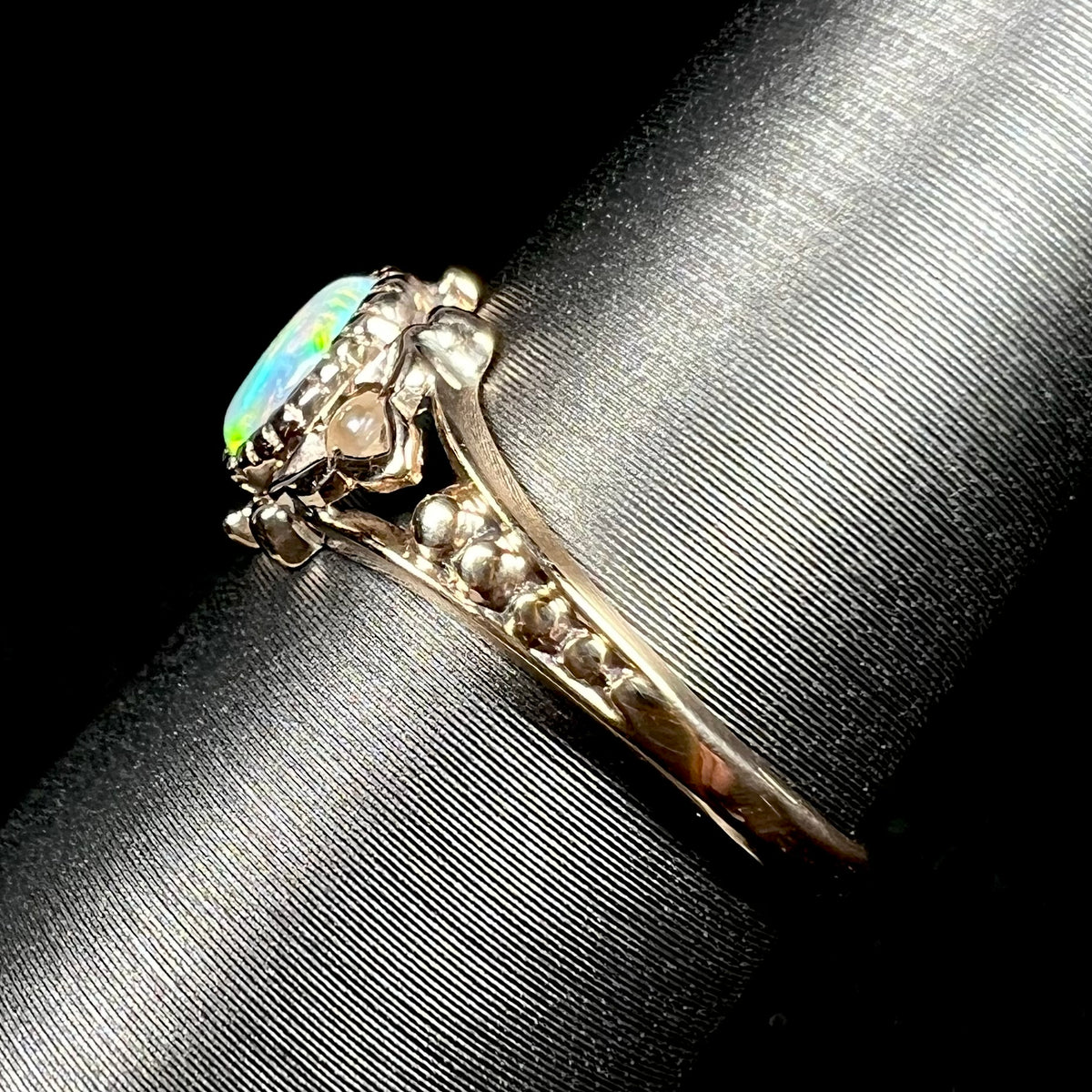Side view of dainty, delicate 9k yellow gold shank on Victorian era opal ring, shown on ring display