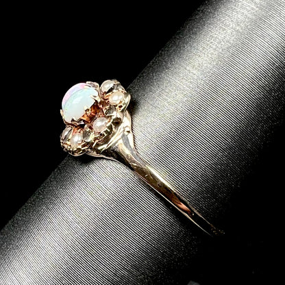 Side view of a Victorian 9k gold opal and pearl ring on a ring display, the ring's dainty gold shank in focus