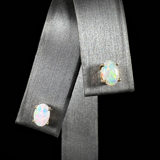 A pair of dainty crystal opal stud earrings in 14k gold, displayed on a black background.