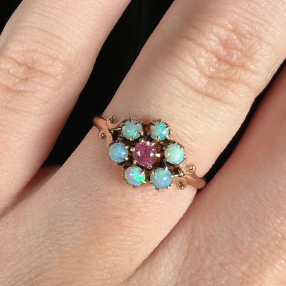 Close-up of dainty Victorian era pink tourmaline and Hungarian opal ring, worn on finger