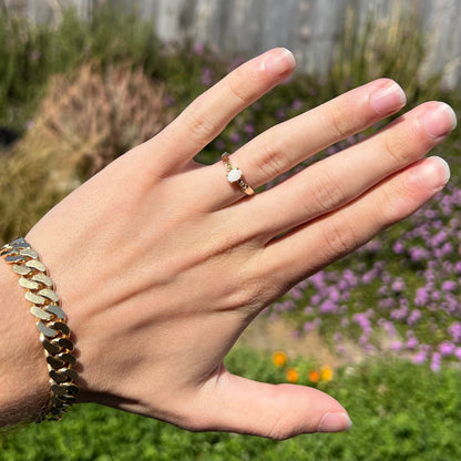 A dainty natural opal and diamond engagement ring in yellow gold.