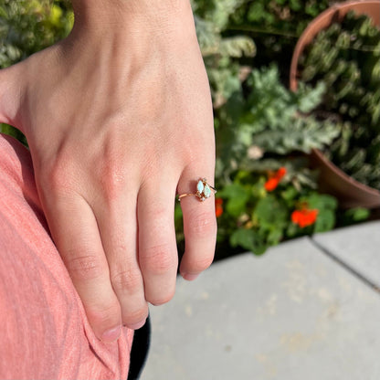 A ladies' gold ring mounted with two marquise cut opals and two diamond accents.