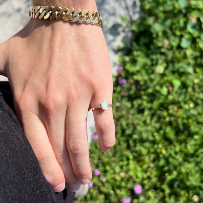 A dainty, 1960's style opal and diamond engagement ring.  The ring is prong-set and yellow gold.