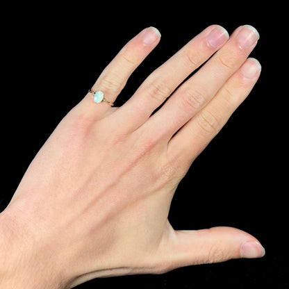 A dainty, 1960's style opal and diamond engagement ring.  The ring is prong-set and yellow gold.