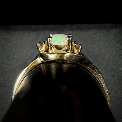 Side gallery view of a delicate 10k yellow gold opal and diamond ring on a ring display.