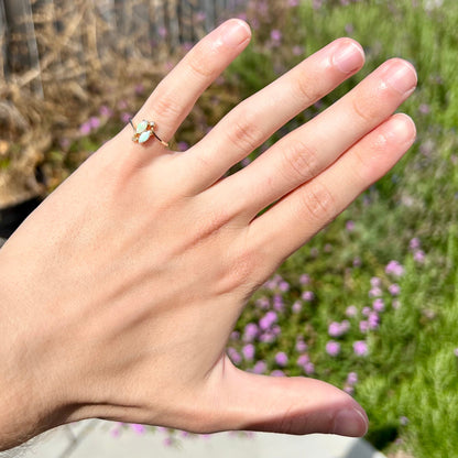 A ladies' gold ring mounted with two marquise cut opals and two diamond accents.