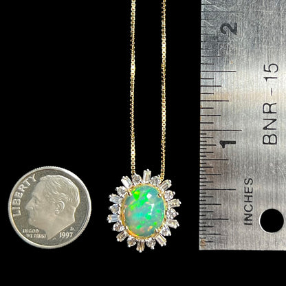 Dime-sized gold Ethiopian fire opal and white sapphire halo pendant shown between US dime coin and ruler for scale.