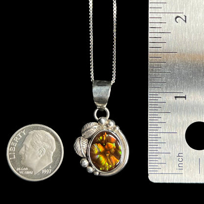 A silver fire agate pendant measuring 1.2 inches long from top of bail shown on chain between US dime coin and ruler.  Excluding the bail, the pendant is roughly the size of the dime.