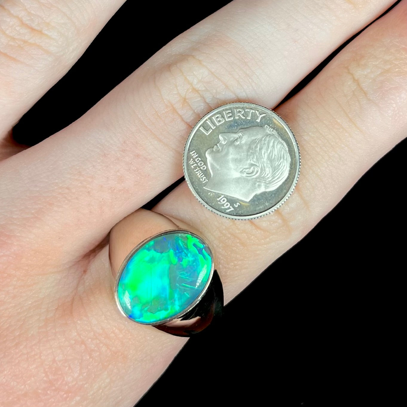 Large blue Australian opal men's ring worn on hand next to US dime coin
