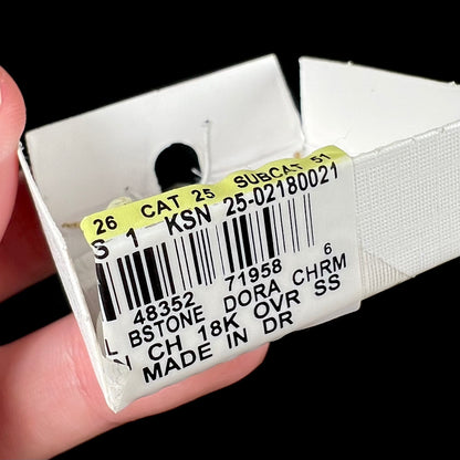 Close-up of a product label with text and barcodes on a packaging component of Jacmel Dora the Explorer necklace box.