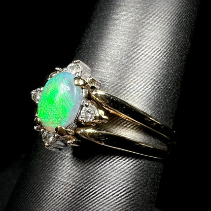 Angled close-up of double-sided opal and diamond flip ring in 14k gold, shown on ring display.  Opal has bright green flash